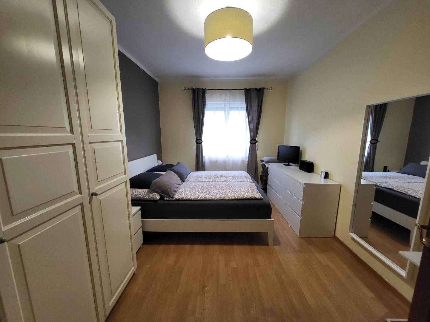 Helles Schlafzimmer mit Doppelbett, Kleiderschrank und Holzboden.
