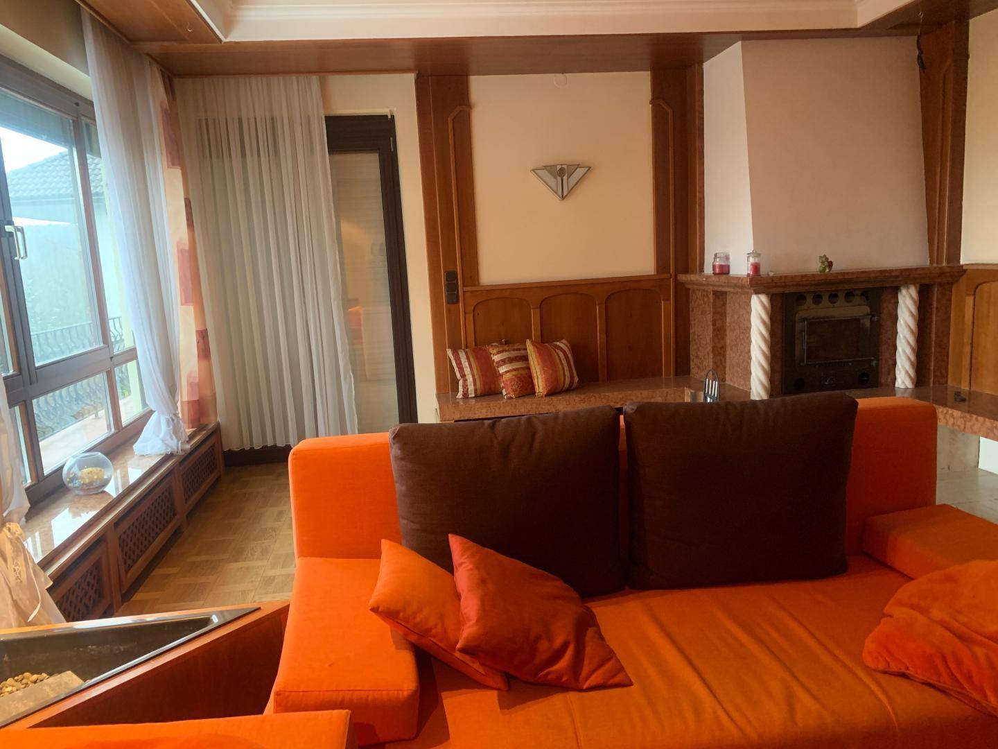 Gemütliches Wohnzimmer mit Kamin, bequemer Couch und traditioneller Holzvertäfelung.