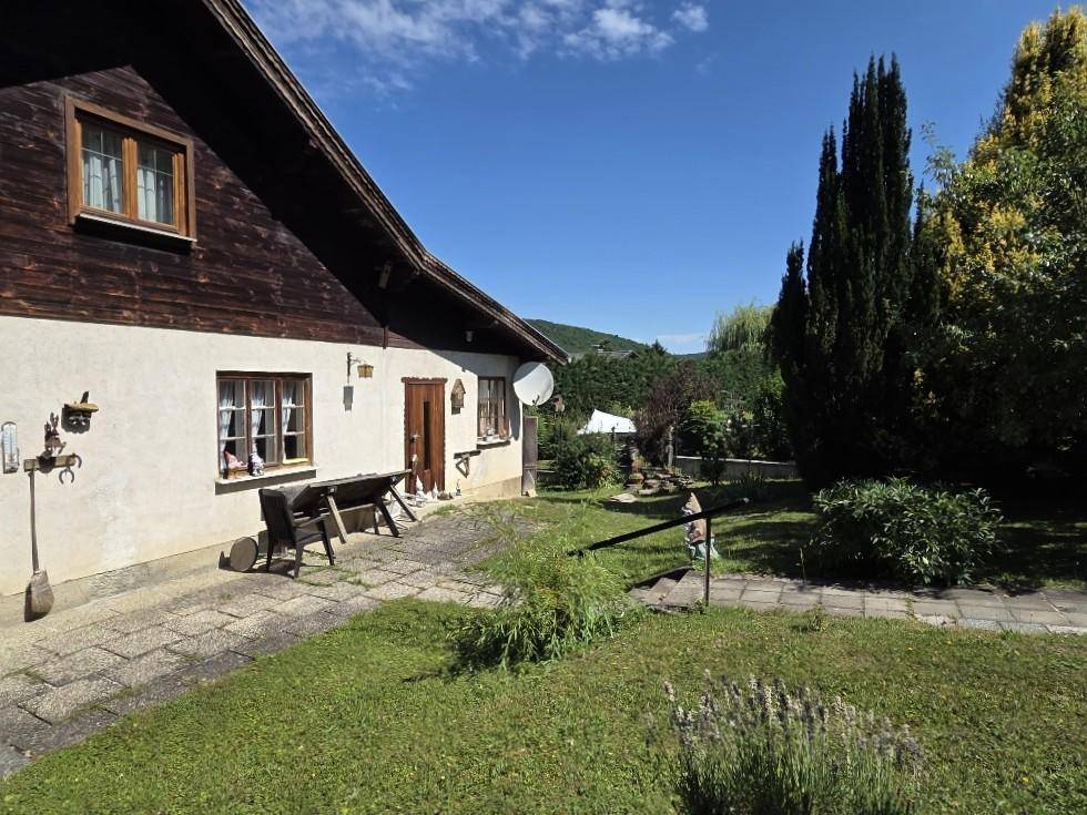 Geräumige Terrasse mit Steinplatten und Blick auf den weitläufigen, grünen Garten.