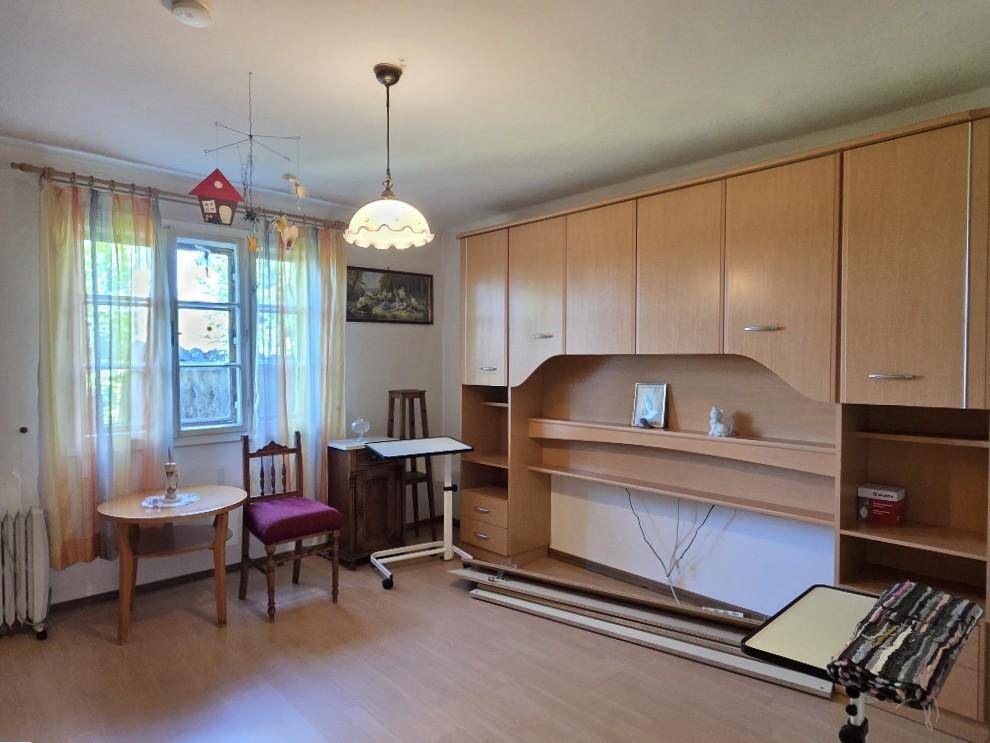 Helles Schlafzimmer mit Einbauschränken, Holzfußboden und Blick ins Grüne.