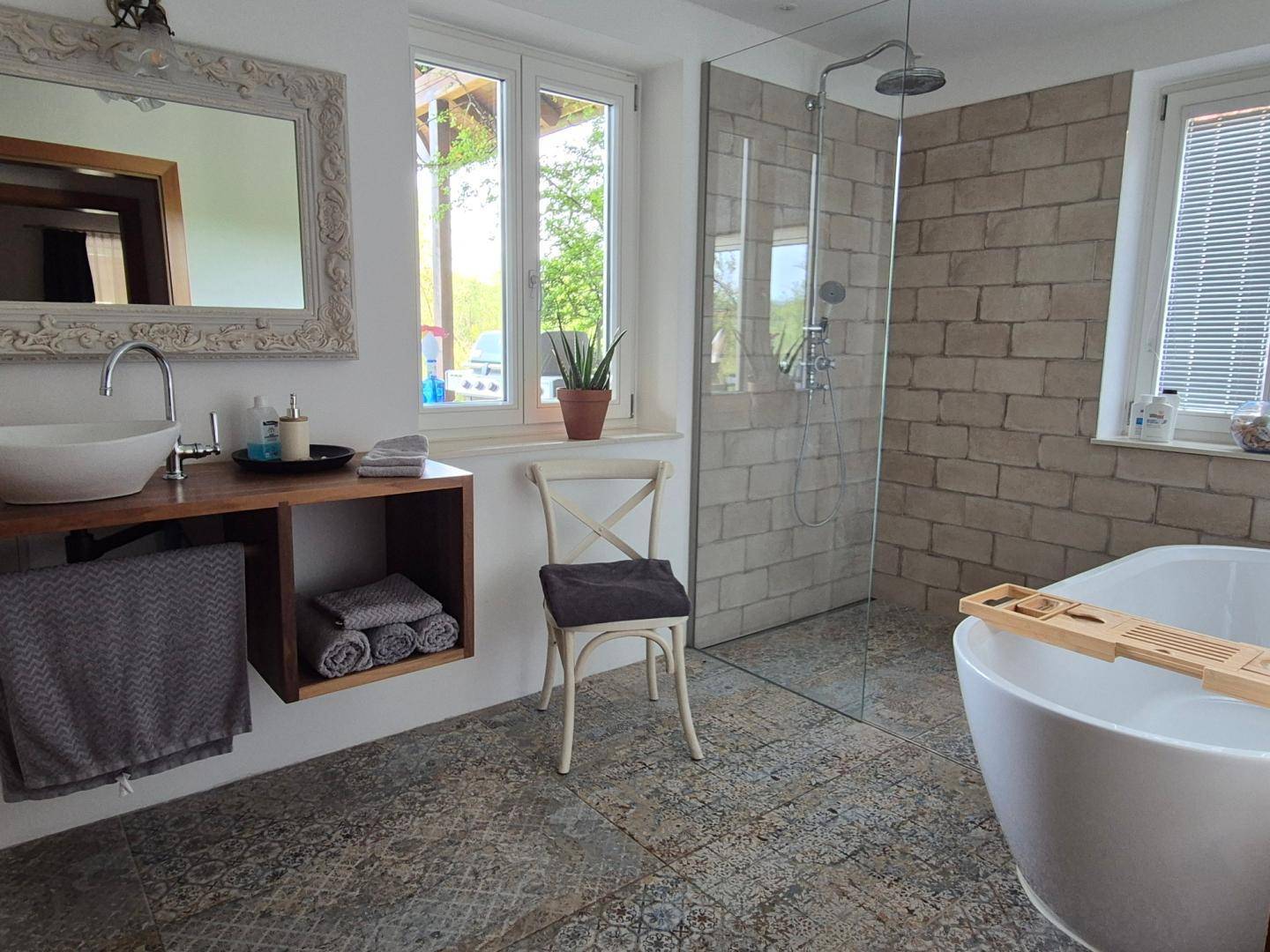 Modernes Badezimmer mit freistehender Badewanne, begehbarer Dusche und großem Fenster für viel Tageslicht.