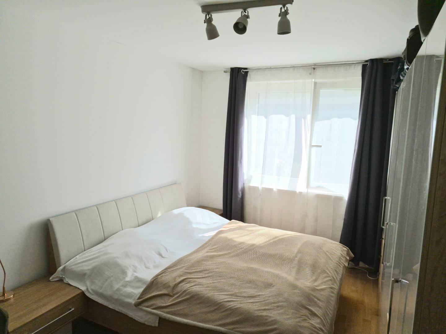 Gemütliches Schlafzimmer mit Holzboden, großem Bett und dunklen Vorhängen für erholsamen Schlaf.