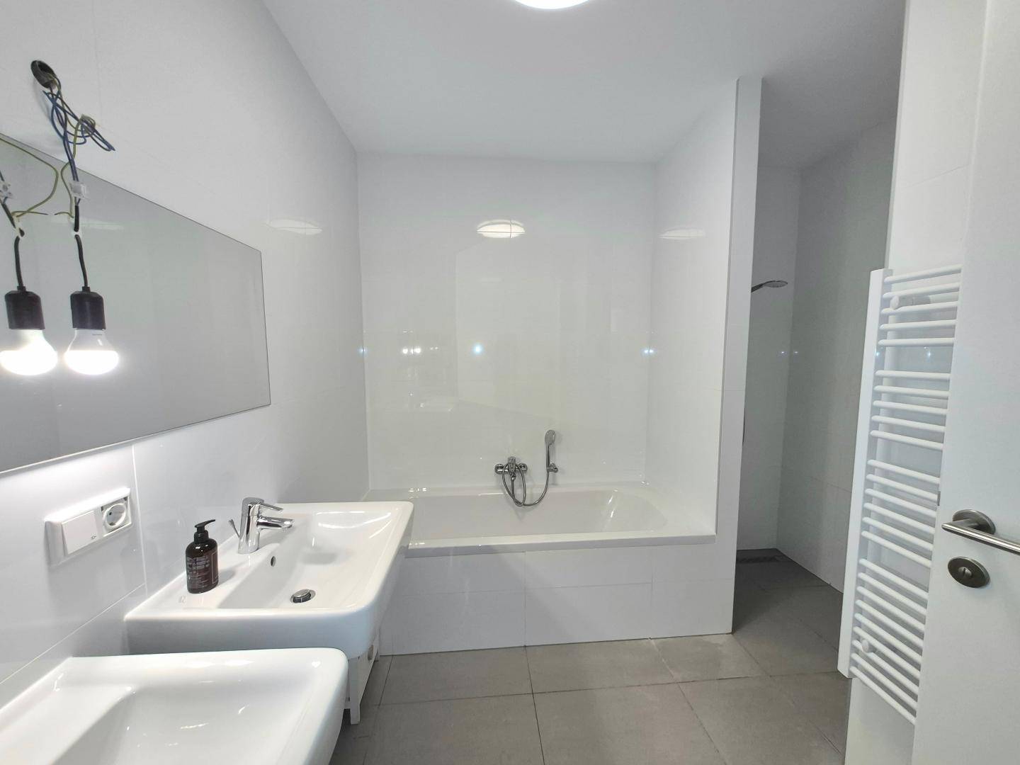 Modernes Badezimmer mit zwei Waschbecken, Badewanne und beheiztem Handtuchhalter.