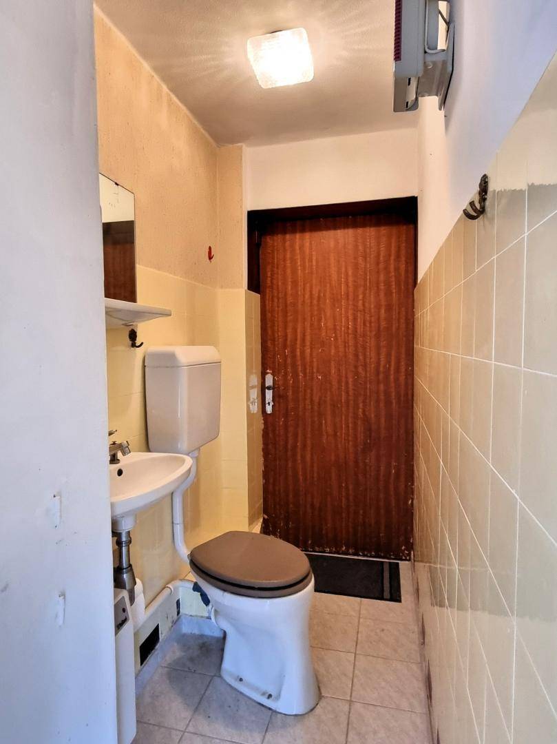 Kleines Gäste-WC mit gelben Fliesen, Toilette und Waschbecken, funktional eingerichtet.