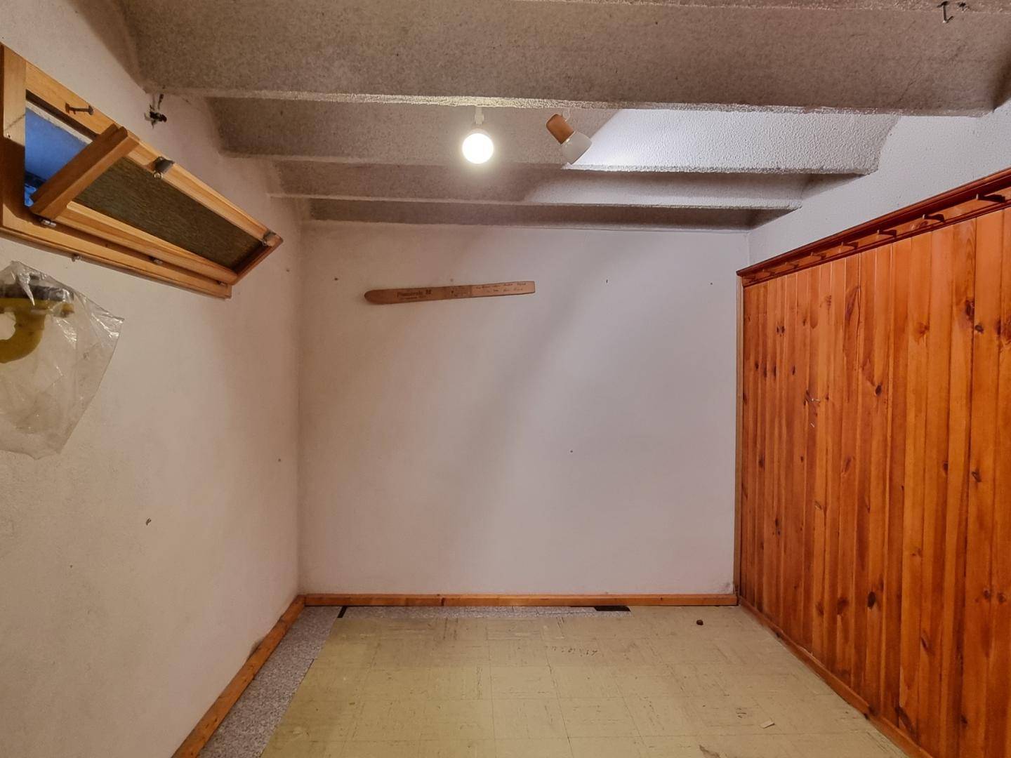 Leerer Raum mit Holzverkleidung, Sichtbetondecke und kleinem Fenster im oberen Bereich.