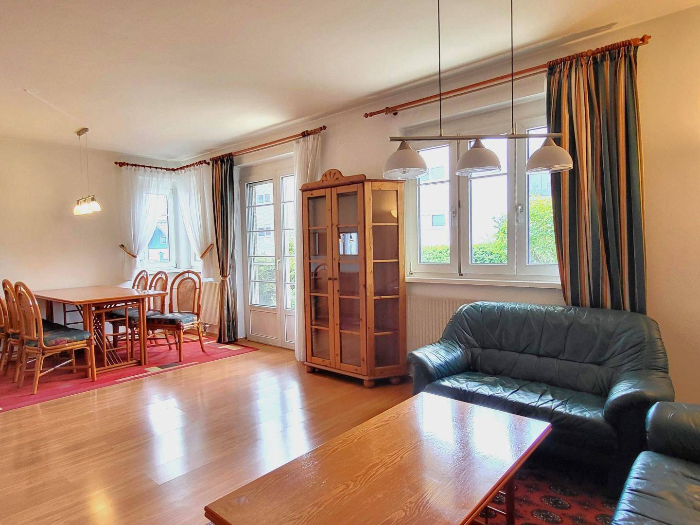 Geräumiger Wohn-Essbereich mit Holzboden, Esstisch und Ledersofas.
