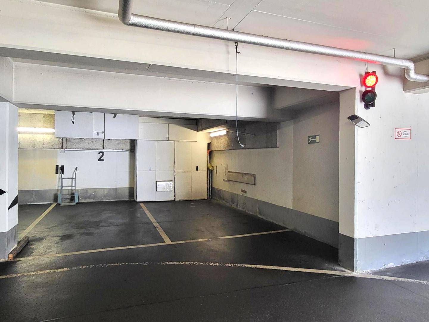 Tiefgarage mit markierten Parkplätzen und Ampelsystem zur Verkehrsregelung.