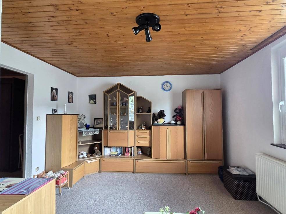 Geräumiges Zimmer mit Holzdecke, Teppichboden und viel Stauraum durch Schränke.