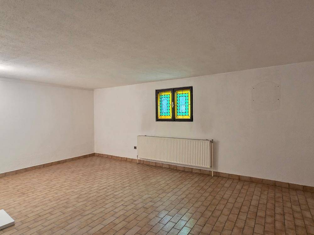 Heller Kellerraum mit Fliesenboden und einem dekorativen Buntglasfenster.
