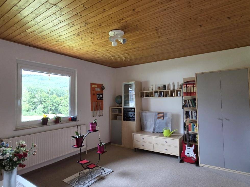 Geräumiges Zimmer mit Holzdecke, Teppichboden und vielseitigen Möbeln.