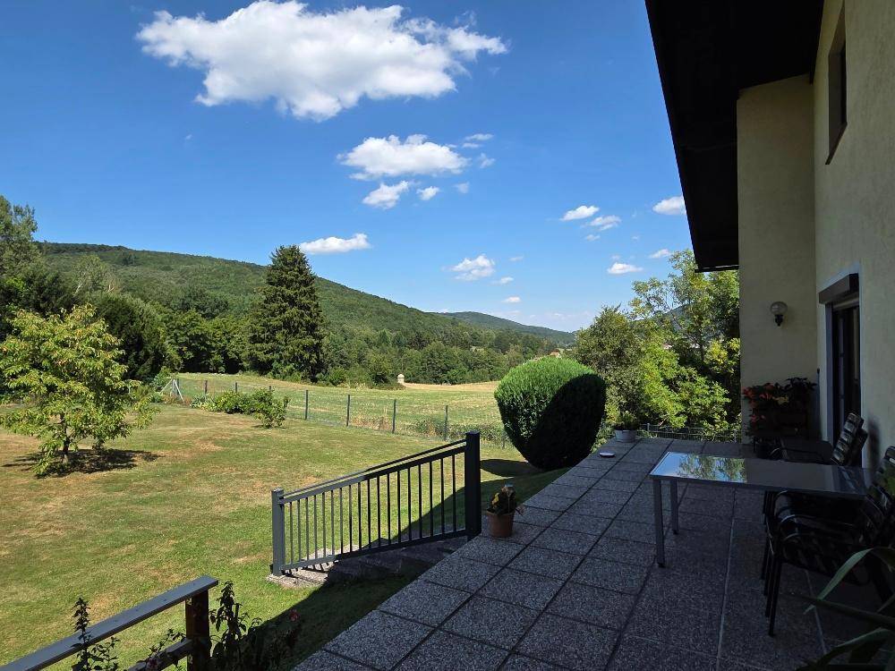 Sonniger Terrassenbereich mit Sitzgelegenheiten und weitem Blick über die grüne Landschaft.