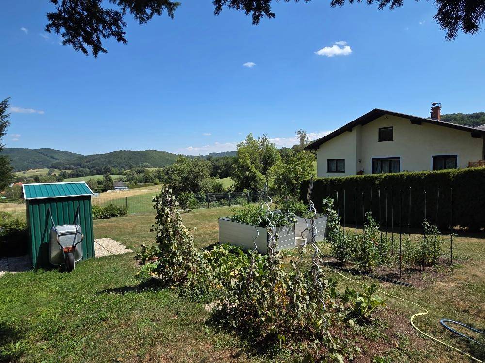 Großer Garten mit Hochbeeten, Geräteschuppen und Blick auf die umliegende Landschaft.