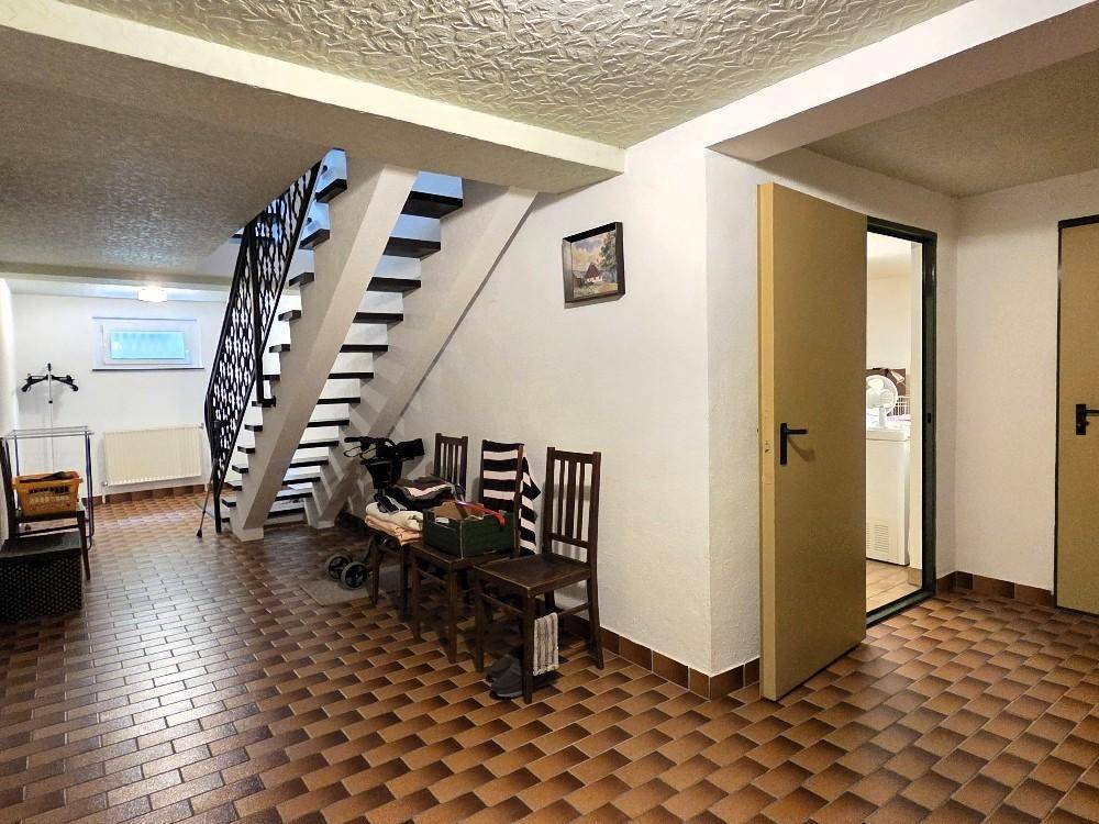 Kellerbereich mit gefliestem Boden und Treppe, die in die oberen Etagen führt.