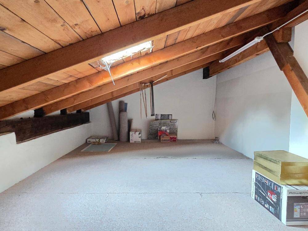 Unausgebauter Dachboden mit sichtbaren Holzbalken und Dachfenster, ideal als Stauraum.