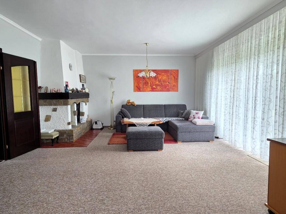 Gemütliches Wohnzimmer mit großem Sofa, Kamin und Zugang zur Terrasse.
