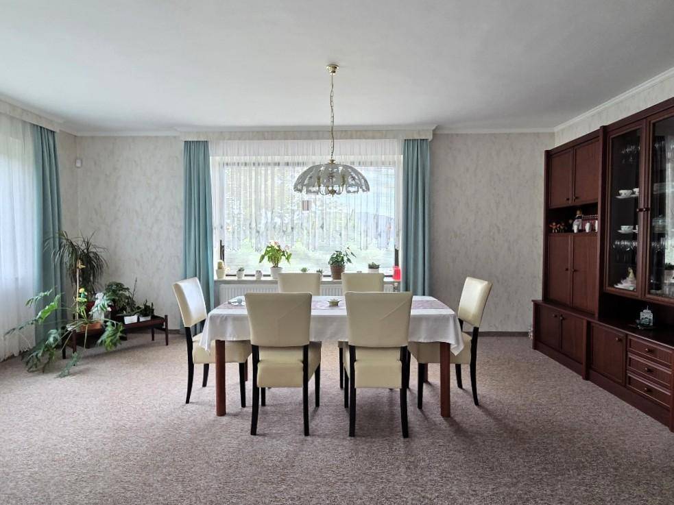 Klassisches Esszimmer mit großem Esstisch, Teppichboden und Blick in den Garten.