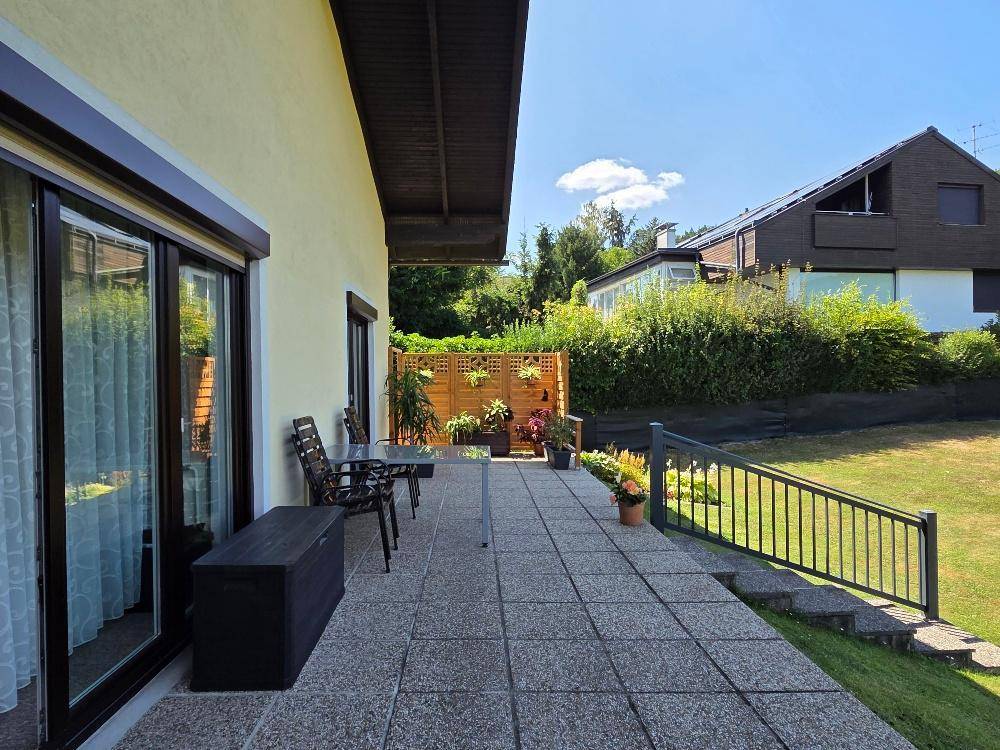 Gepflasterte Terrasse mit Gartenmöbeln und Sichtschutz, angrenzend an den Garten.