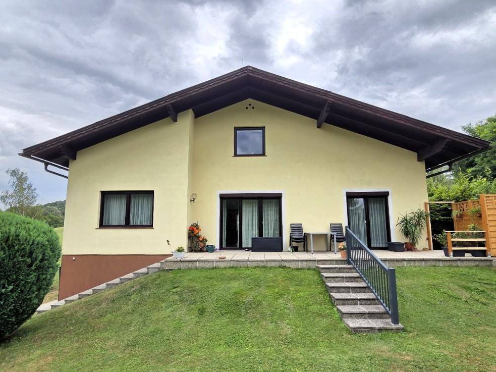 Rückseite des Hauses mit Terrasse und Treppe zum Garten unter bewölktem Himmel.