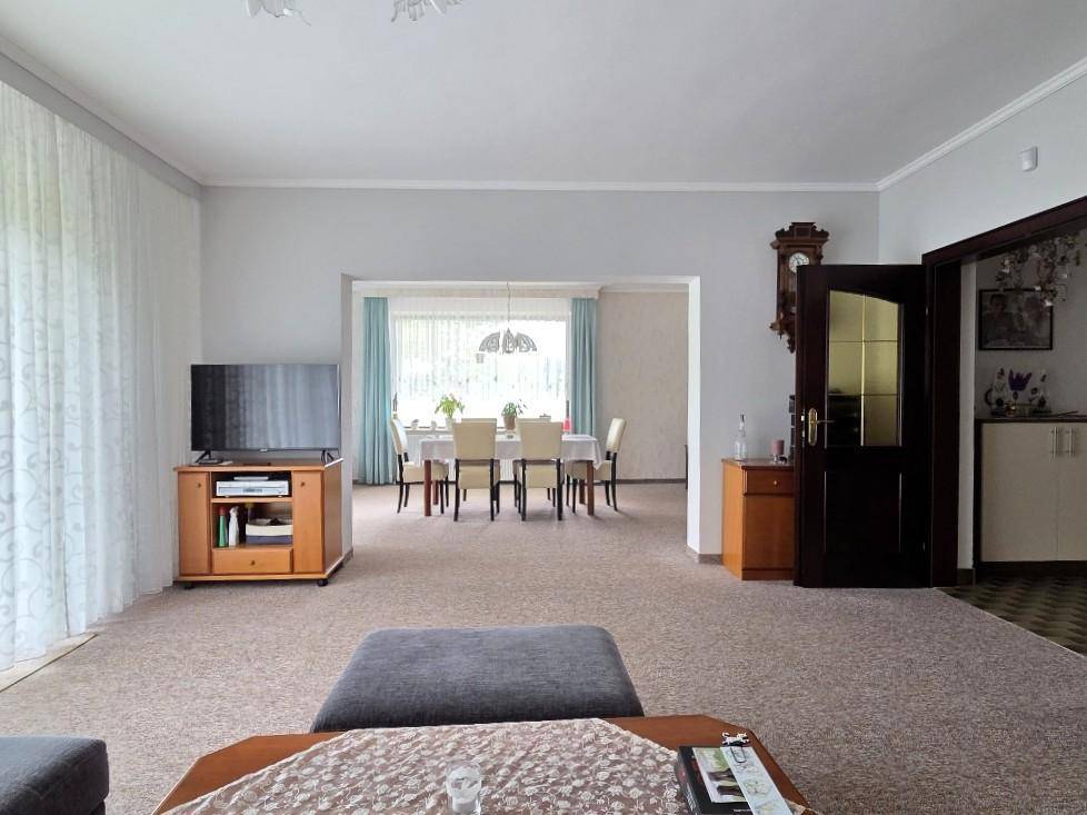 Geräumiger Wohnbereich mit Teppichboden und offenem Zugang zum angrenzenden Esszimmer.