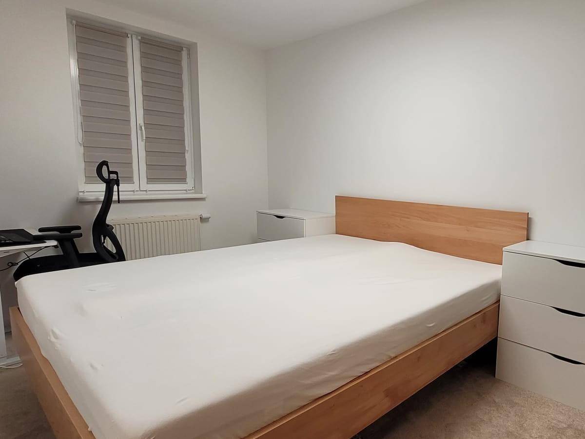 Helles Schlafzimmer mit Holzbett, Nachttischen und Fenster, bietet eine ruhige Atmosphäre.