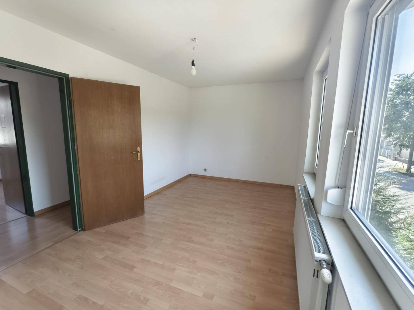 Freundliches Zimmer mit Laminatboden und Fenster, bietet viel Tageslicht.