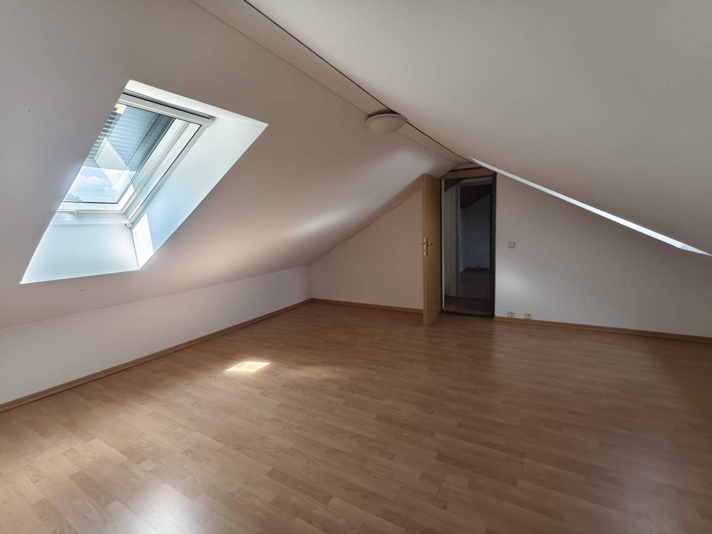 Ausgebauter Dachbodenraum mit Laminatboden und Dachfenster für natürliches Licht.