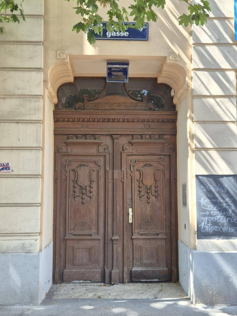 Detailansicht der reich verzierten Holzeingangstür eines historischen Gebäudes mit Straßenschild.