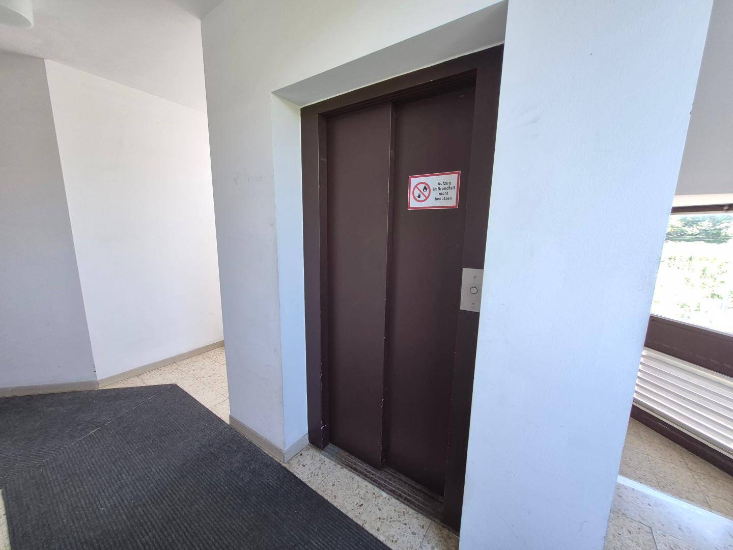 Aufzugstür in einem hellen Treppenhaus, bietet bequemen Zugang zu den Etagen.