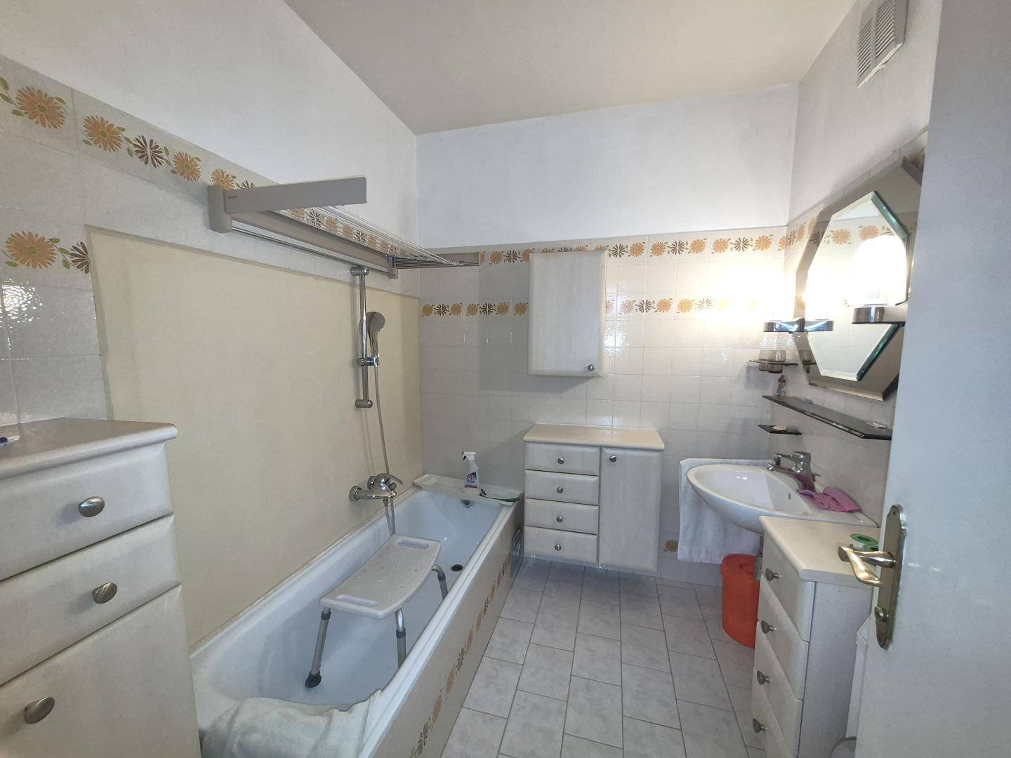 Badezimmer mit Badewanne, Waschbecken und Fliesen im 80er-Jahre-Stil.