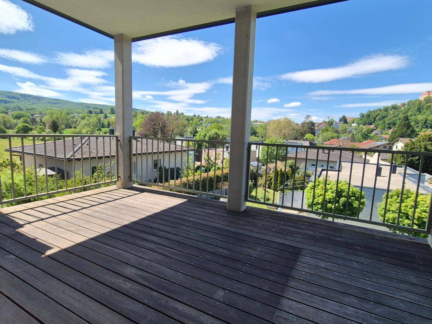 Großer Außenbalkon mit Holzdielen und weitem Panoramablick über die umliegende Landschaft.