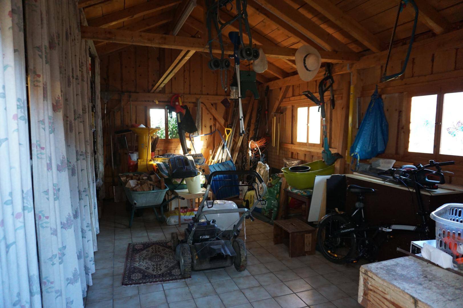 Geräumiger Abstellraum mit Holzverkleidung und Fliesenboden, gefüllt mit Gartengeräten.