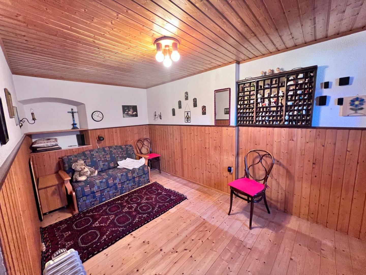 Gemütlicher Wohnraum mit Holzvertäfelung, Holzboden und traditioneller Einrichtung.