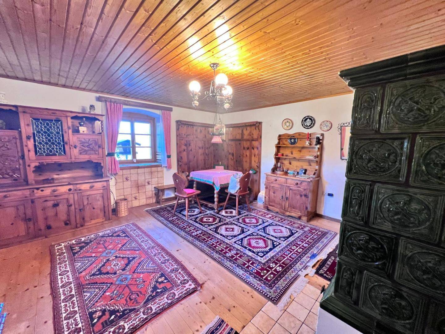 Traditioneller Essbereich mit Holzboden, Holzdecke und einem Kachelofen.