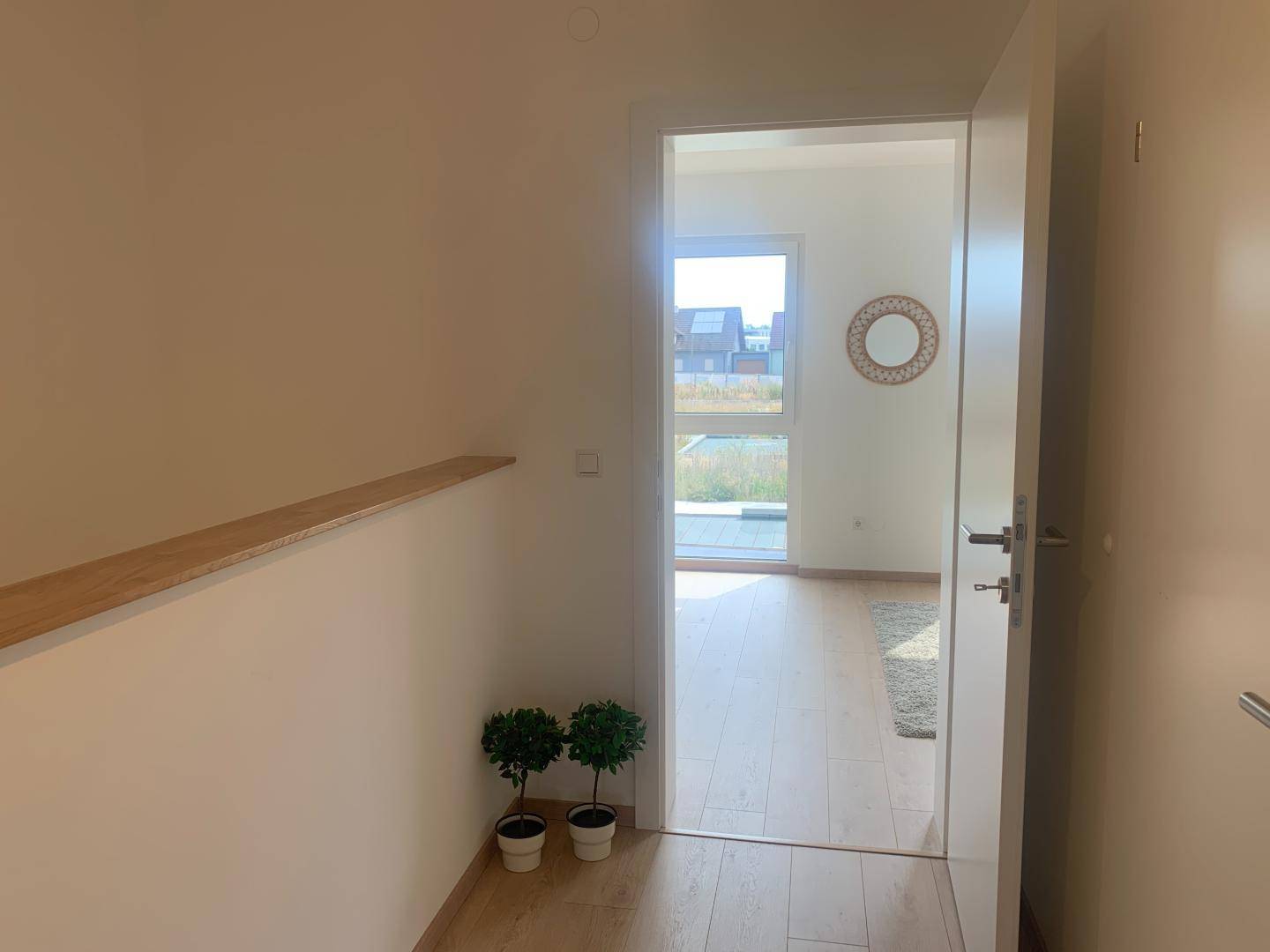 Heller Flur mit Blick in ein angrenzendes Zimmer und dekorativen Pflanzen.