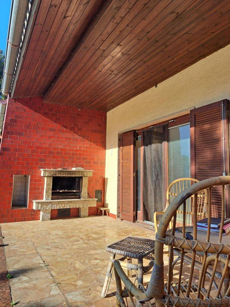 Überdachte Terrasse mit gefliestem Boden, Außenkamin und Korbmöbeln für entspannte Stunden.