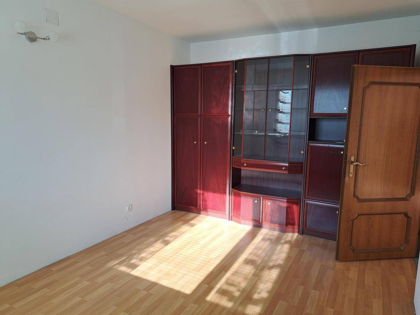Schlafzimmer mit Holzboden und einer großen, dunklen Schrankwand, gut beleuchtet.