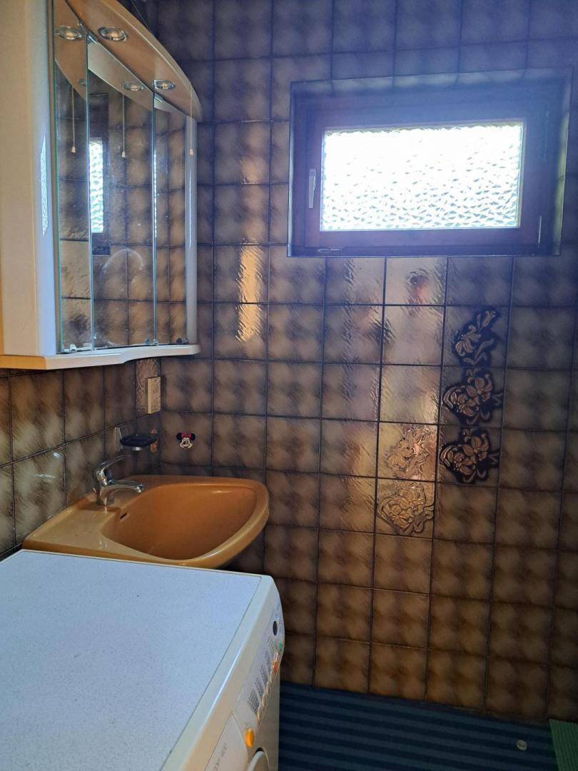 Badezimmer mit gemusterten Fliesen, Waschbecken und einem Spiegelschrank über dem Waschbecken.