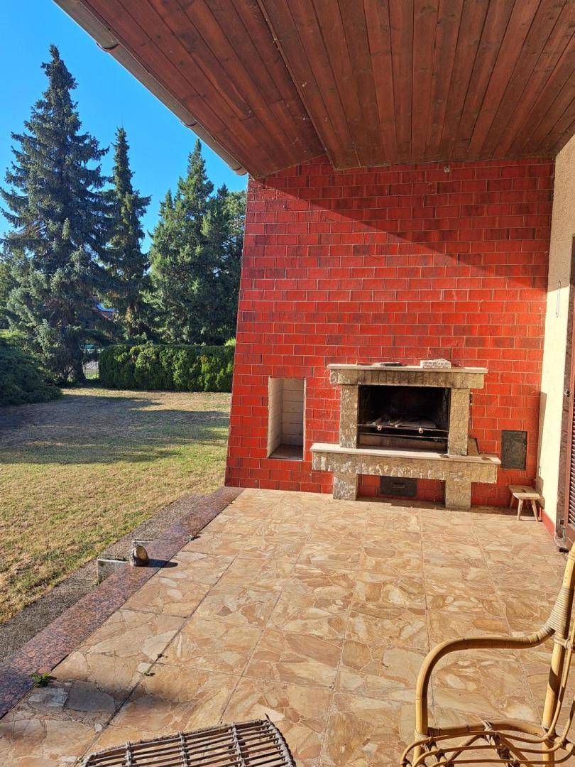 Detailansicht der Terrasse mit Außenkamin, gefliestem Boden und Blick ins Grüne.
