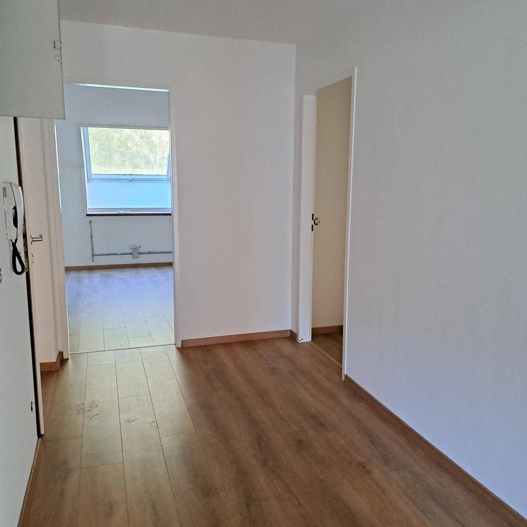 Heller Flur mit Laminatboden und Übergang zu weiteren Räumen, die viel Tageslicht erhalten.