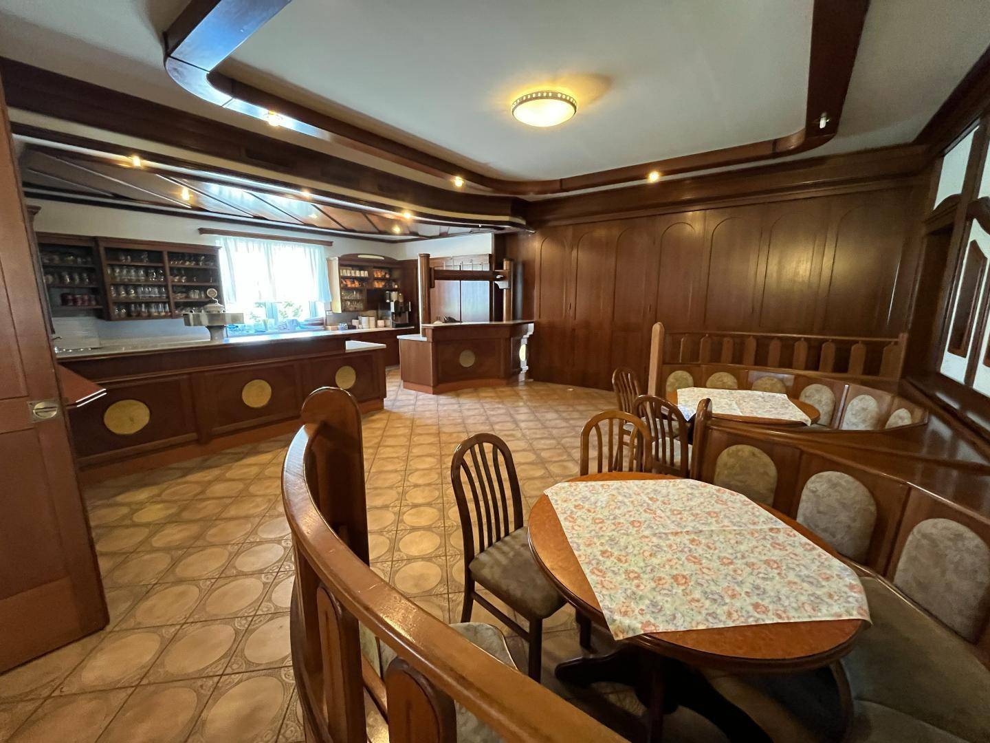 Traditionelle Bar mit Holzeinrichtung, gepolsterten Sitzgelegenheiten und gefliestem Boden.