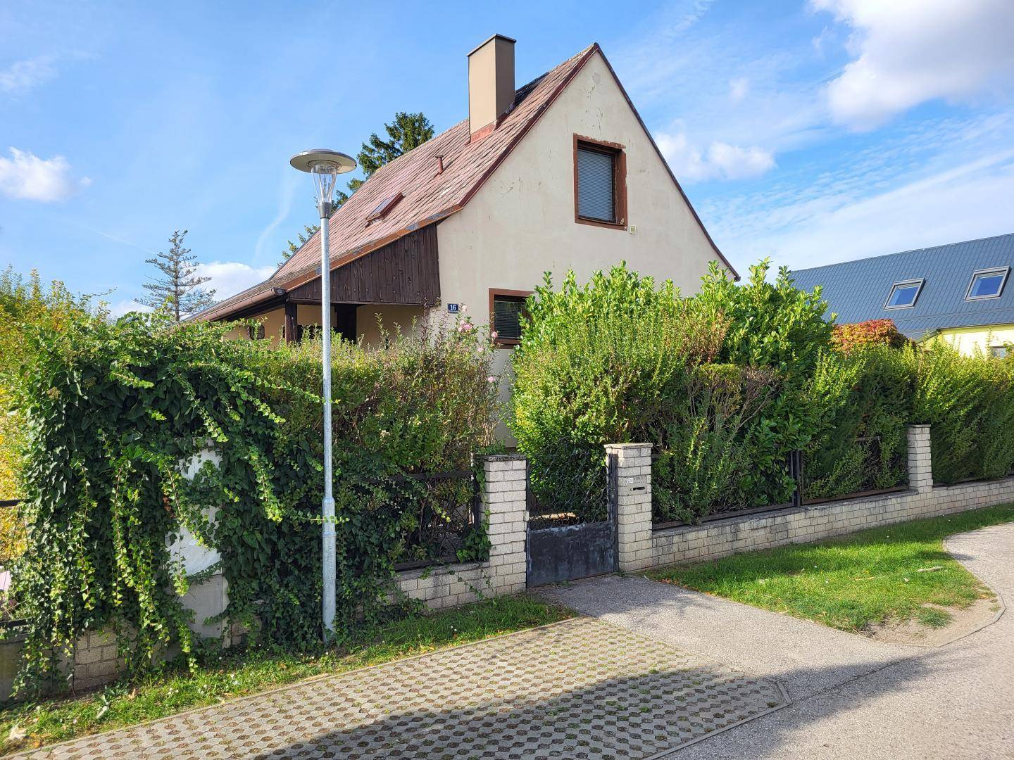 Ansicht des Hauses von der Straße mit gepflegtem Vorgarten und Zaun.