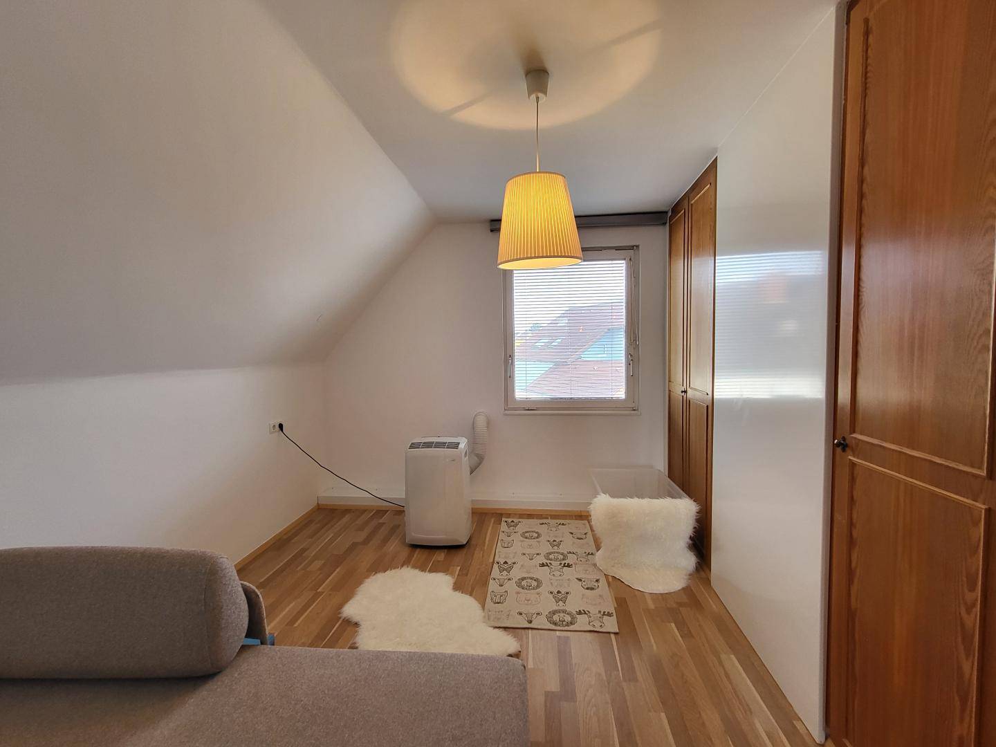 Dachgeschosszimmer mit schrägen Wänden, Holzboden und praktischen Einbauschränken.