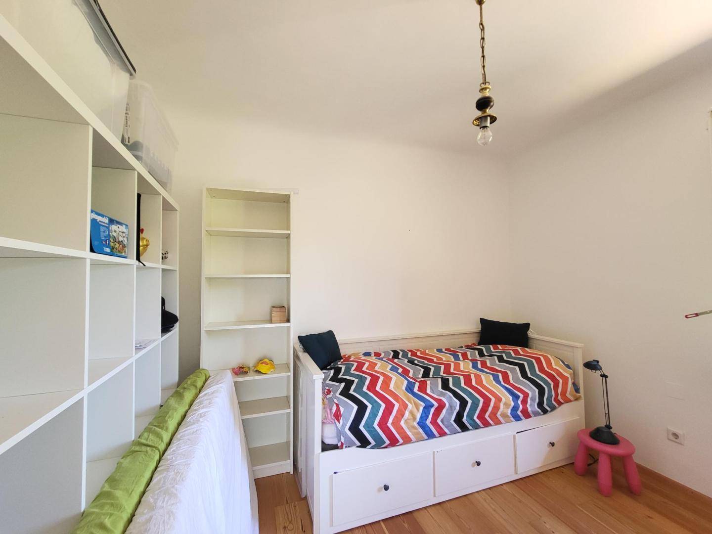 Kinderzimmer oder Gästezimmer mit Holzboden, Einzelbett und Bücherregalen.