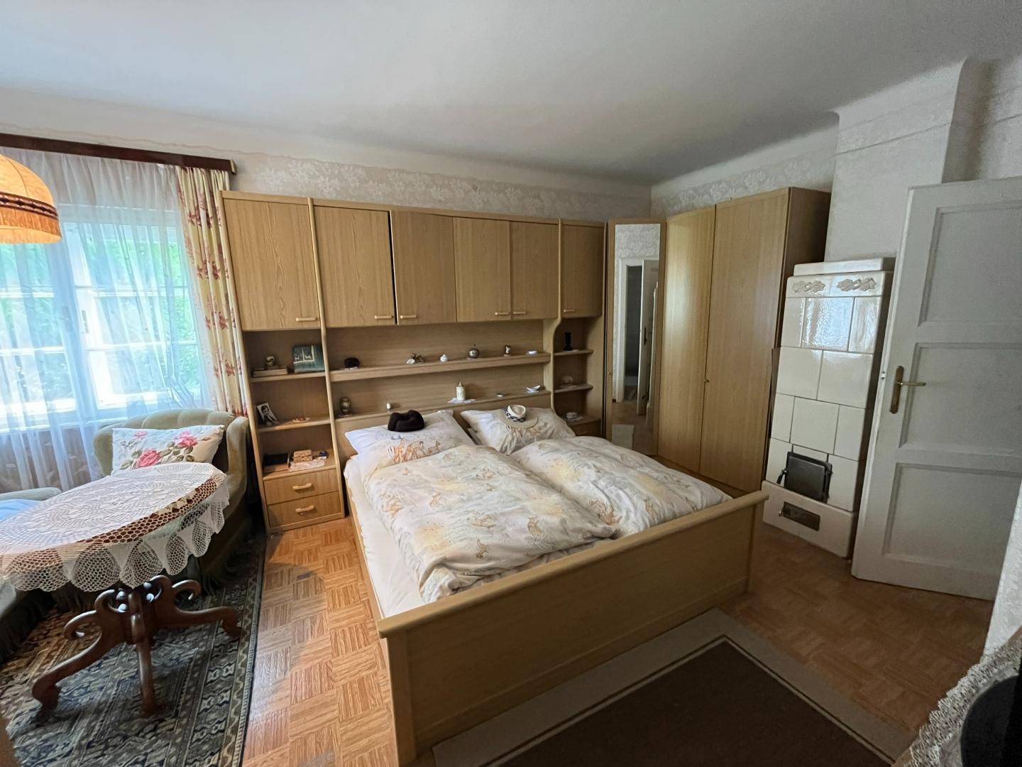Geräumiges Schlafzimmer mit Doppelbett, Einbauschränken und Kachelofen.