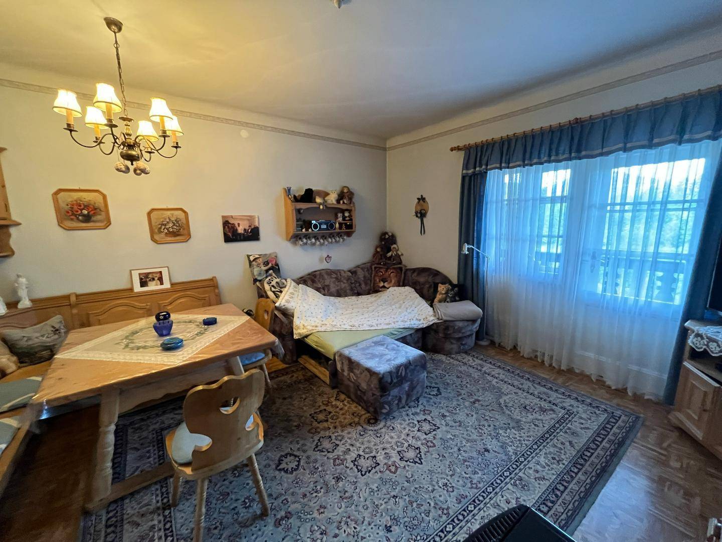 Gemütliches Wohnzimmer mit traditionellen Möbeln, Teppich und Kronleuchter.