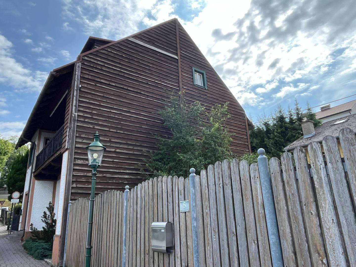 Seitenansicht des Hauses mit Holzverkleidung und traditioneller Architektur.