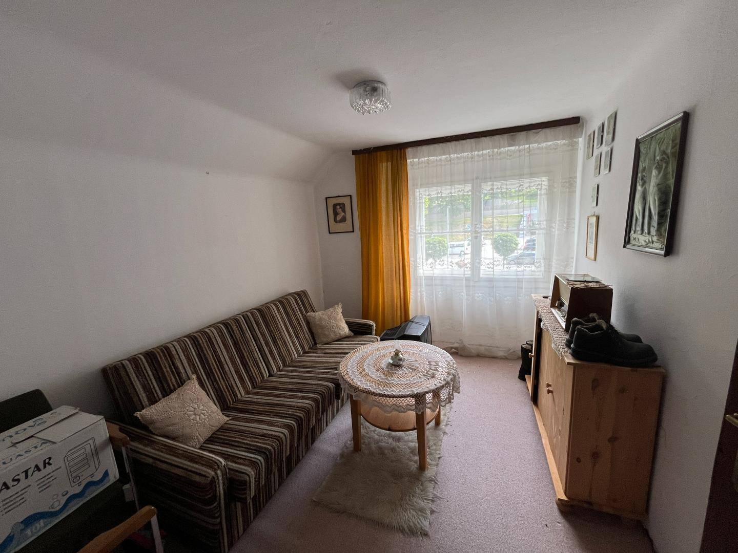 Kleines Wohnzimmer mit Sofa, Couchtisch und Fenster, einfach eingerichtet.