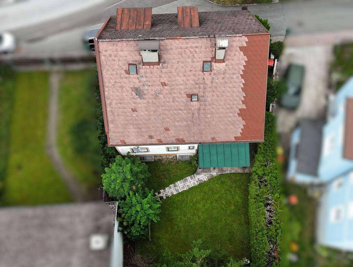 Luftaufnahme des Hauses mit Garten, Rasenfläche und Dach mit Gauben.