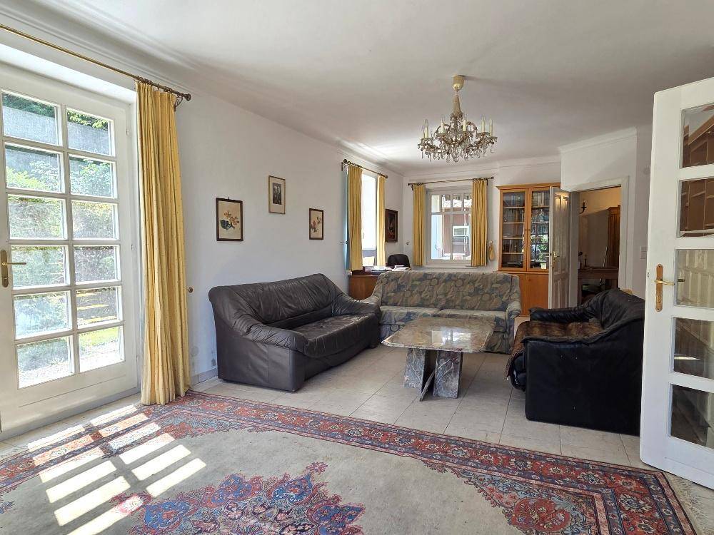 Geräumiges Wohnzimmer mit Fliesenboden, Ledersofas und Blick in den Garten.