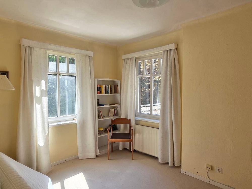 Schlafzimmer mit Teppichboden, Bücherregal und hellen Wänden.
